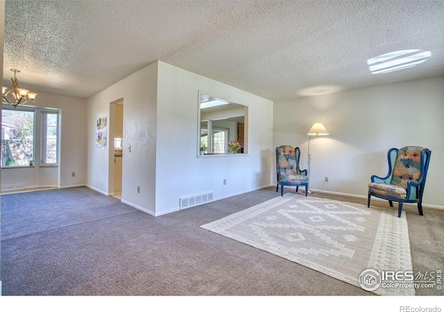 unfurnished room featuring visible vents, baseboards, a textured ceiling, a chandelier, and carpet