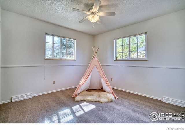 playroom featuring carpet floors, ceiling fan, a textured ceiling, and visible vents
