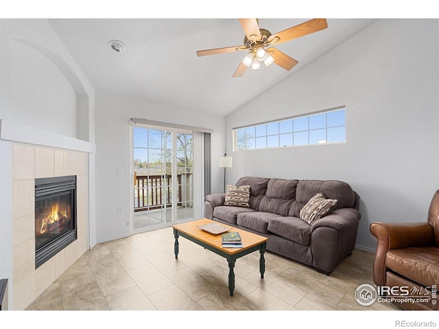 living room with a tiled fireplace, ceiling fan, and high vaulted ceiling