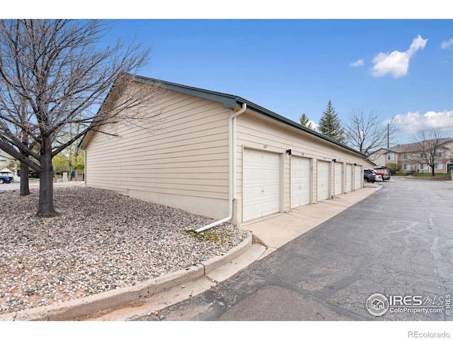 view of home's exterior featuring an outbuilding and community garages