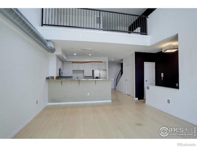 kitchen with a towering ceiling, light countertops, a peninsula, a breakfast bar, and stainless steel appliances
