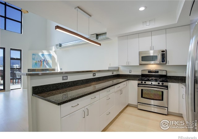 1200 Yarmouth Ave Unit 238, Boulder, CO 80304 - kitchen with visible vents, white cabinetry, a peninsula, stainless steel appliances, and light wood-style flooring