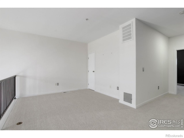 carpeted spare room featuring baseboards and visible vents