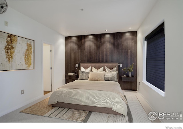 bedroom featuring wooden walls, baseboards, light carpet, and recessed lighting