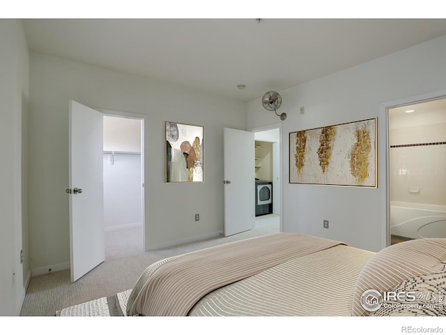 bedroom featuring light carpet, a walk in closet, washer / clothes dryer, baseboards, and a closet