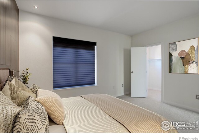 carpeted bedroom featuring recessed lighting, baseboards, and a walk in closet
