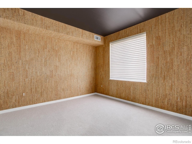 carpeted empty room with baseboards, visible vents, and wallpapered walls