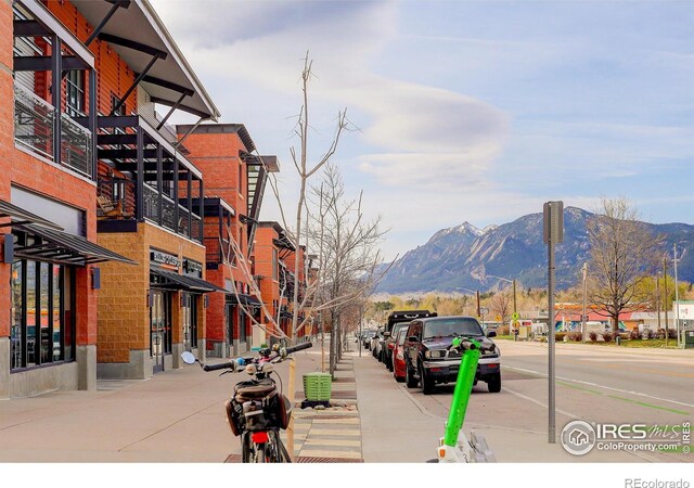 view of road featuring sidewalks, a mountain view, street lighting, and curbs