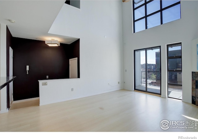 1200 Yarmouth Ave Unit 238, Boulder, CO 80304 - unfurnished living room with a towering ceiling, wood finished floors, and a healthy amount of sunlight