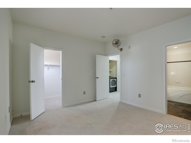 unfurnished bedroom with carpet floors, baseboards, ensuite bathroom, washer / clothes dryer, and a spacious closet