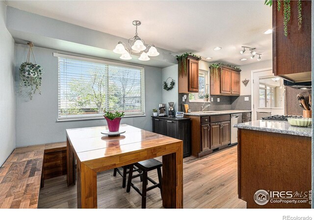 7960 Estes Ct, Arvada, CO 80005 - kitchen featuring dishwasher, light countertops, light wood finished floors, backsplash, and a notable chandelier