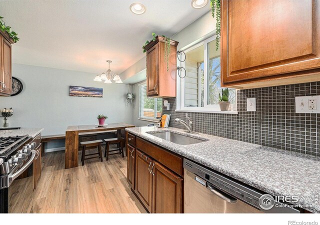 7960 Estes Ct, Arvada, CO 80005 - kitchen featuring appliances with stainless steel finishes, an inviting chandelier, a sink, light wood-style floors, and tasteful backsplash
