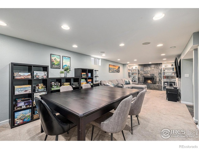 dining space featuring recessed lighting, baseboards, a stone fireplace, and light carpet