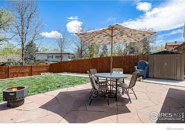 7960 Estes Ct, Arvada, CO 80005 - view of patio featuring outdoor dining area, a storage shed, an outbuilding, a fenced backyard, and an outdoor fire pit