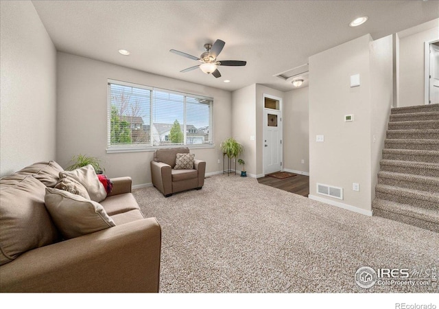 carpeted living area with a ceiling fan, visible vents, stairway, baseboards, and recessed lighting