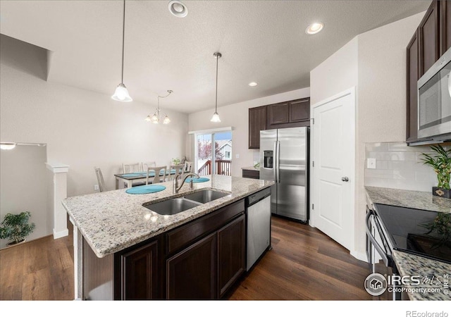 kitchen featuring a kitchen island with sink, dark wood-style flooring, appliances with stainless steel finishes, dark brown cabinets, and a sink