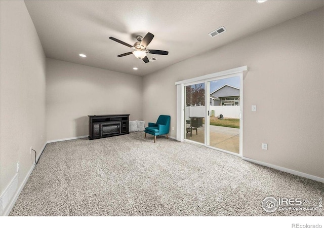 living area featuring visible vents, a ceiling fan, carpet, and baseboards