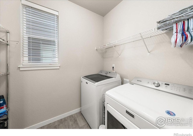 washroom with baseboards, laundry area, light wood finished floors, and independent washer and dryer