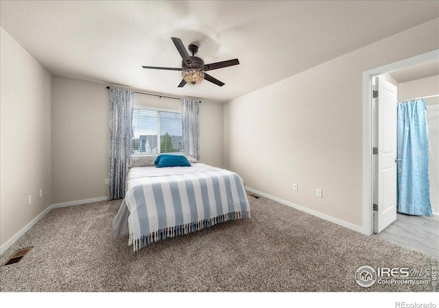 bedroom with ceiling fan, a textured ceiling, visible vents, carpet floors, and baseboards