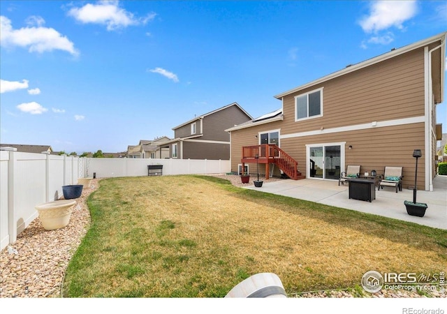 back of property featuring a deck, a fenced backyard, a patio area, a yard, and stairway