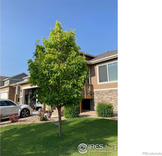 view of front of home with a garage, a front yard, a deck, and stone siding