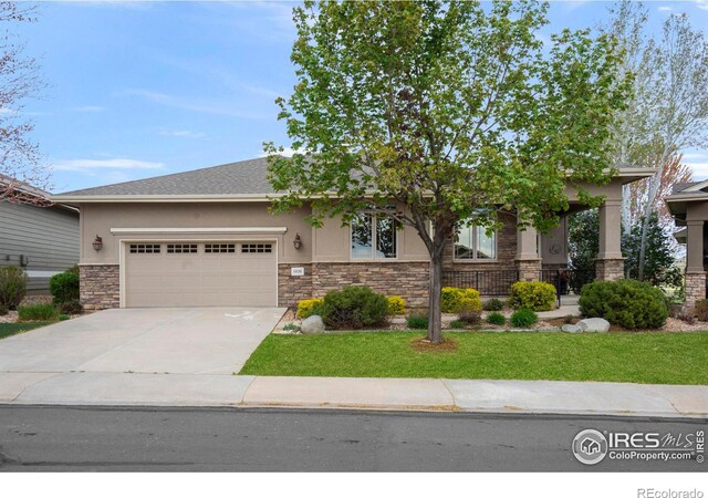 6836 Spanish Bay Dr, Windsor, CO 80550 - view of front of house featuring a front yard, a garage, concrete driveway, stone siding, and stucco siding