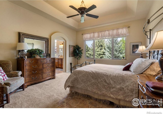 6836 Spanish Bay Dr, Windsor, CO 80550 - bedroom with carpet floors, ensuite bathroom, ceiling fan, a tray ceiling, and arched walkways