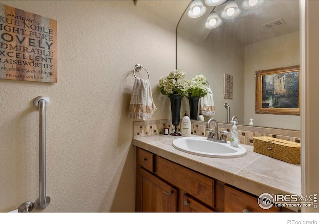 6836 Spanish Bay Dr, Windsor, CO 80550 - bathroom with vanity, tasteful backsplash, and visible vents