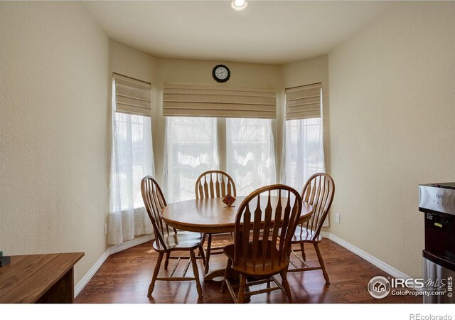 dining room featuring baseboards, a textured wall, and wood finished floors