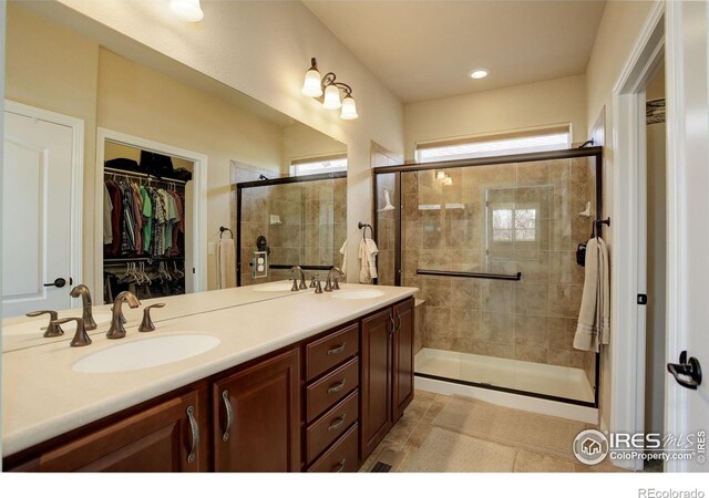 bathroom with double vanity, a sink, and a stall shower