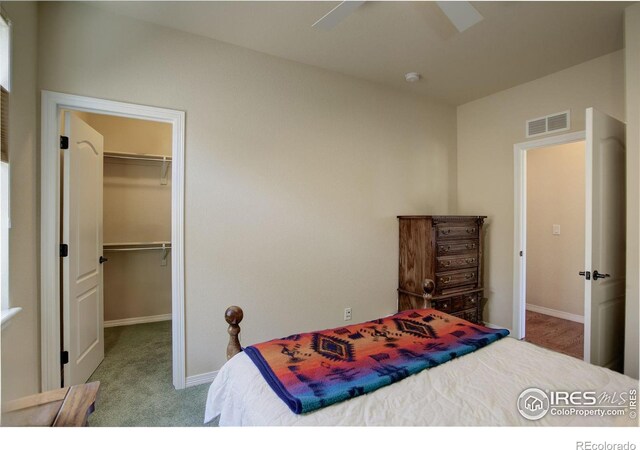 carpeted bedroom with a ceiling fan, visible vents, baseboards, a closet, and a spacious closet