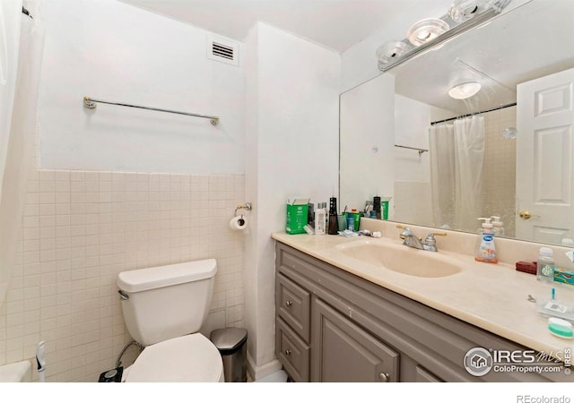 bathroom with vanity, toilet, tile walls, a shower with curtain, and visible vents