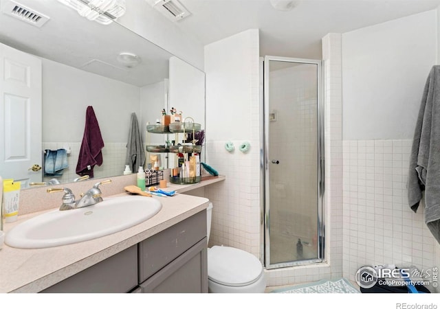 bathroom with toilet, tile walls, visible vents, and a stall shower