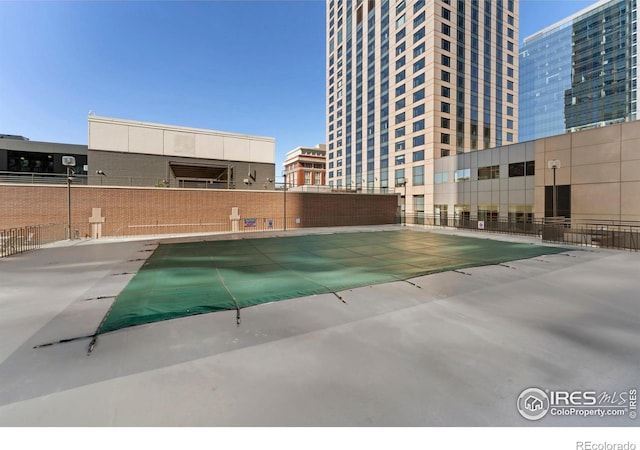 view of swimming pool featuring a view of city and fence