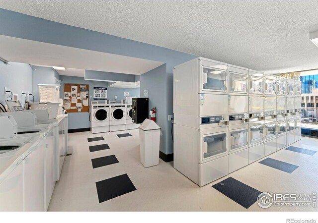 kitchen featuring a textured ceiling, washing machine and clothes dryer, stacked washing maching and dryer, tile patterned floors, and baseboards