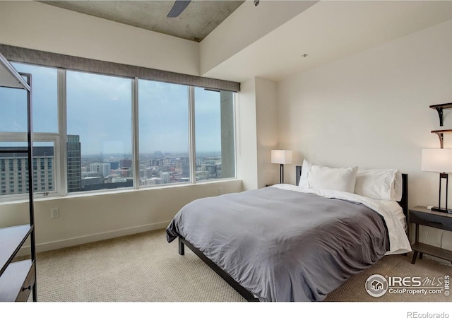 carpeted bedroom featuring baseboards, ceiling fan, and a city view