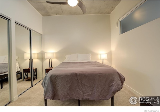 bedroom with baseboards, carpet, a ceiling fan, and two closets