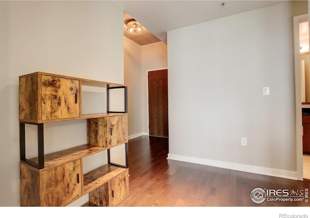 spare room with baseboards and wood finished floors