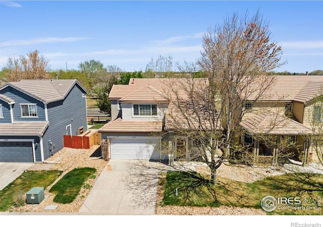 traditional home with a garage, fence, a tiled roof, and driveway