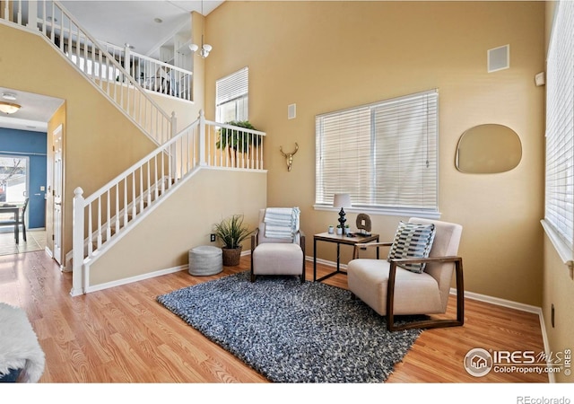 living area with baseboards, stairs, a towering ceiling, and wood finished floors