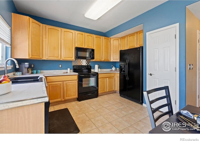 kitchen with light countertops, a sink, black appliances, and light brown cabinets