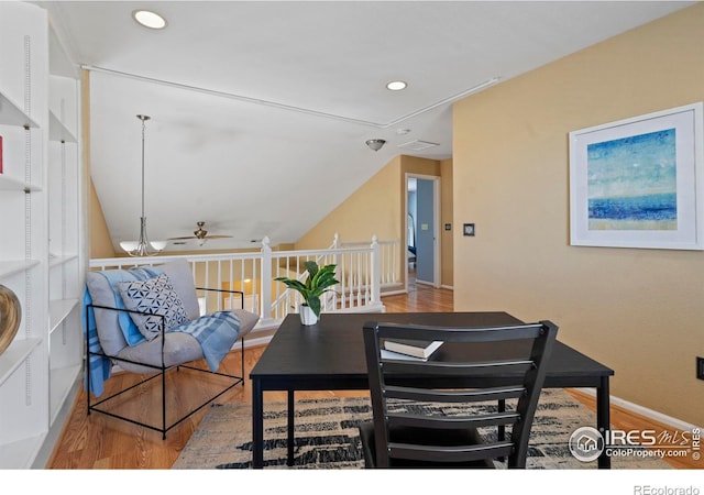 dining space featuring a ceiling fan, baseboards, wood finished floors, and lofted ceiling