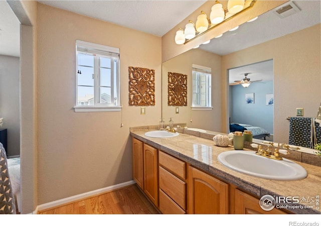 bathroom featuring a sink, ensuite bath, wood finished floors, and a wealth of natural light