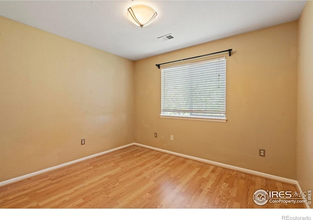 empty room featuring baseboards, visible vents, and wood finished floors