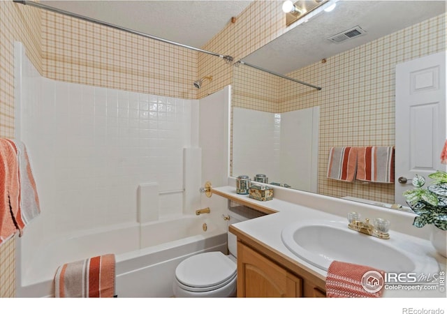 bathroom with vanity, bathtub / shower combination, toilet, a textured ceiling, and visible vents