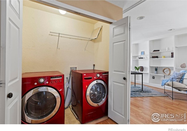 clothes washing area featuring laundry area, washer and clothes dryer, and wood finished floors