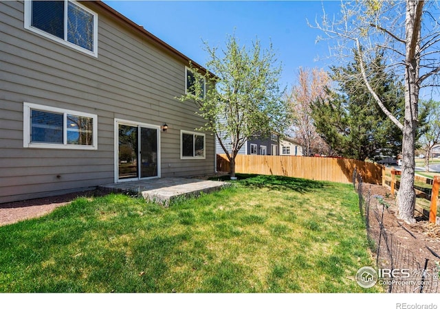 rear view of property featuring fence, a patio, and a lawn
