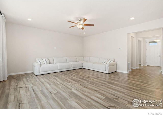 unfurnished living room featuring baseboards, a ceiling fan, light wood finished floors, and recessed lighting