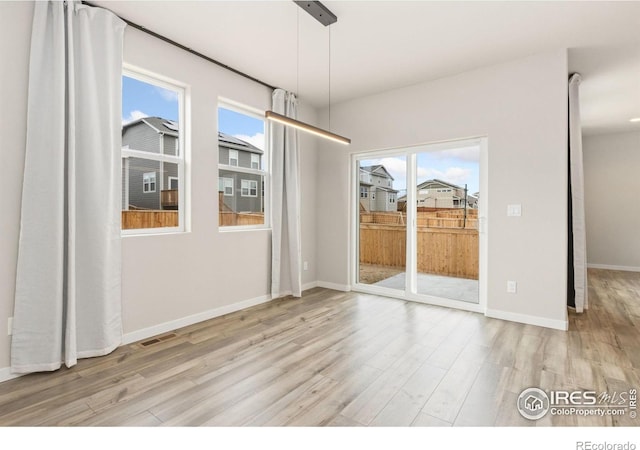 unfurnished dining area featuring visible vents, baseboards, wood finished floors, and a healthy amount of sunlight
