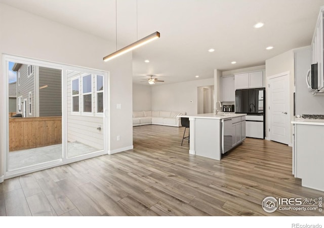 kitchen with a kitchen breakfast bar, open floor plan, light wood-style floors, stainless steel appliances, and recessed lighting